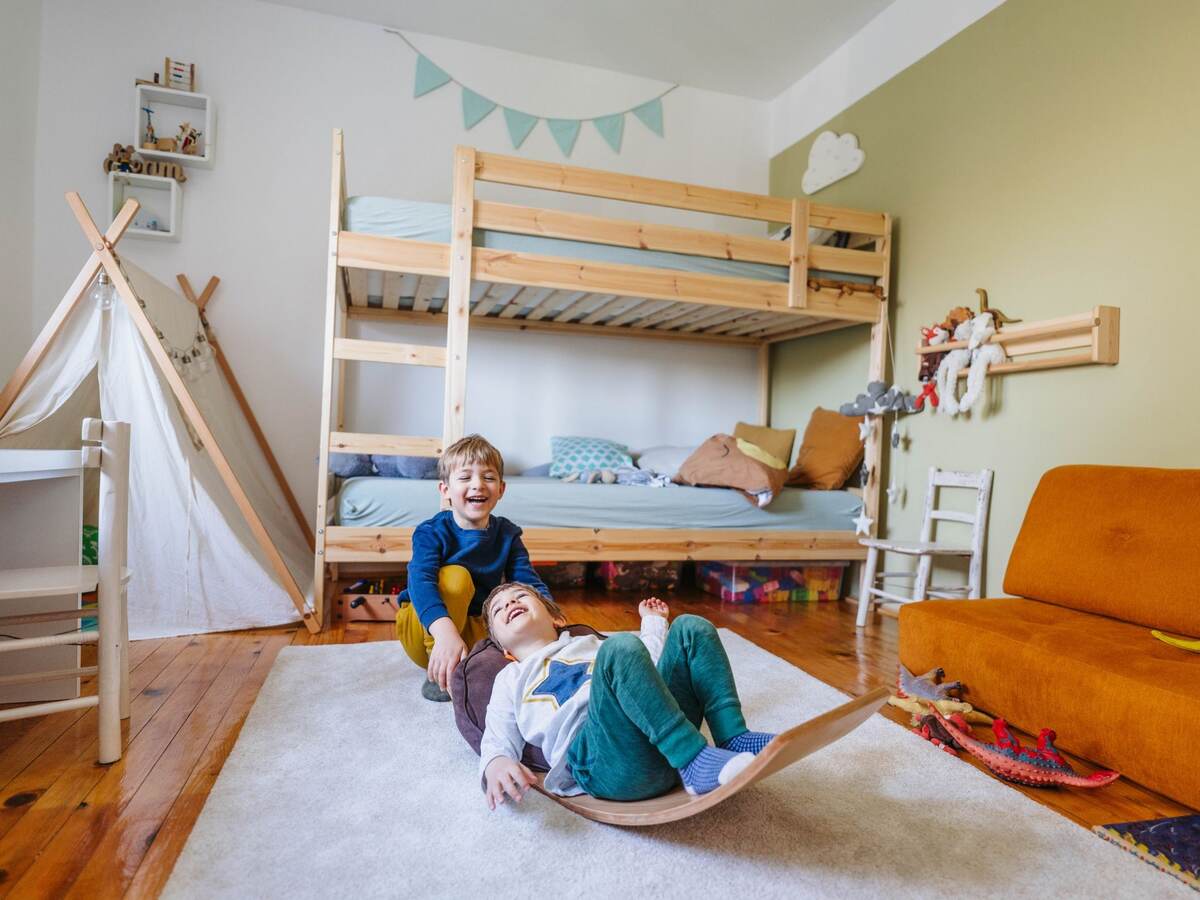 Two little boys playing in their room in front of their bunk bed.